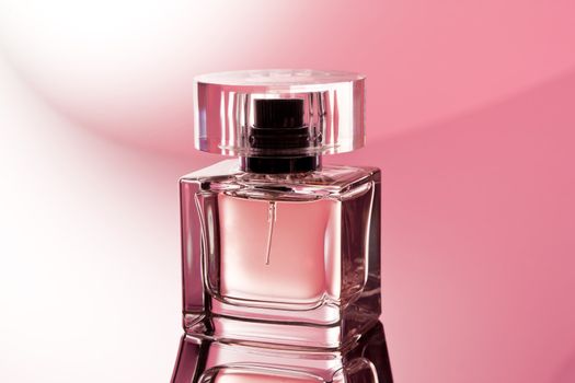 glass of perfume over abstract pink background