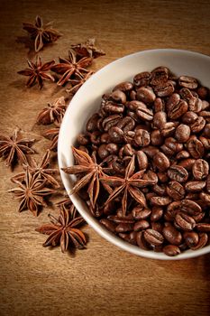 Bowl of coffee beans and spice on wood