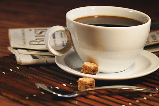 Coffee cup and newspaper. Focus on handle of cup