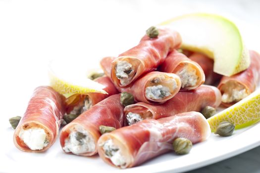 Parma ham rolls filled with cream cheese, Galia melon and capers