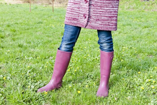 detail of woman wearing rubber boots on spring meadow