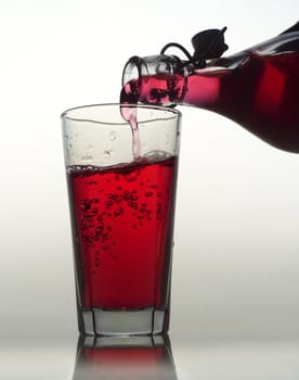 Pouring Red Lemonade in a glass on white background