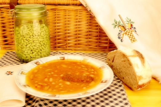 plate of beans with chorizo, Spanish traditional and homemade bread on wooden table