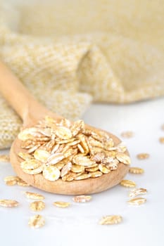 close up of oat flakes in wooden spoon on white background with clipping path 