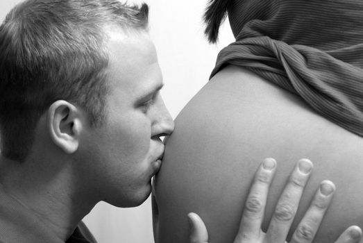 A man kissing his unborn childs pregnant belly.