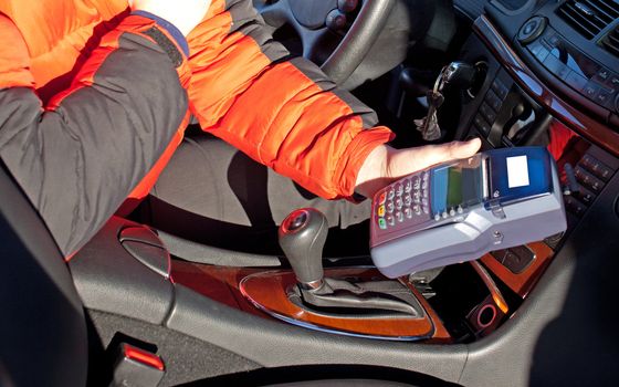 Credit card reader in taxi drivers hand in car