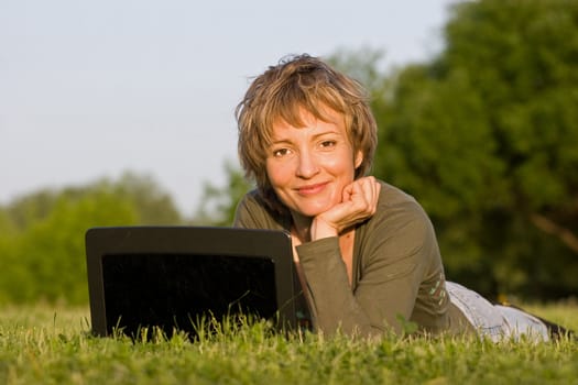 Woman with notebook lying on the grass in park