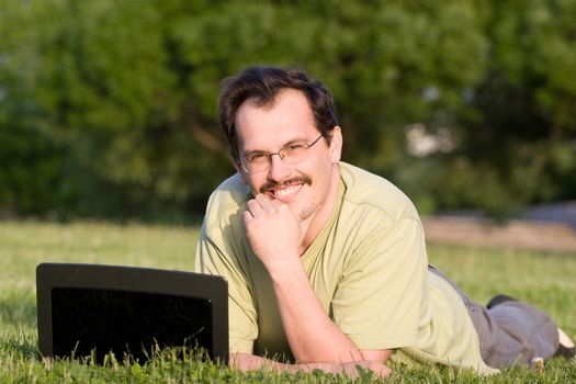 Man with notebook lying on the grass in park