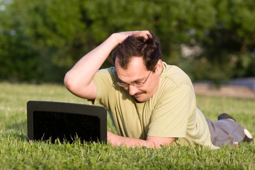 Man with notebook lying on the grass in park