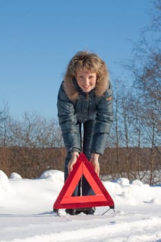 Woman with a warning triangle in sunny winter day