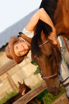 Woman in hat embrace brown horse