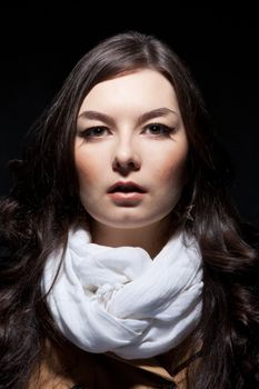 Expressive fashion studio shot of young and beautiful woman wearing brown overcoat on dark background. (Professional makeup and hair style).