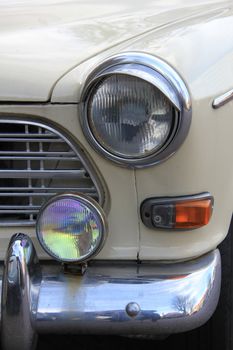 A vintage cream white car front, details of light and bumper