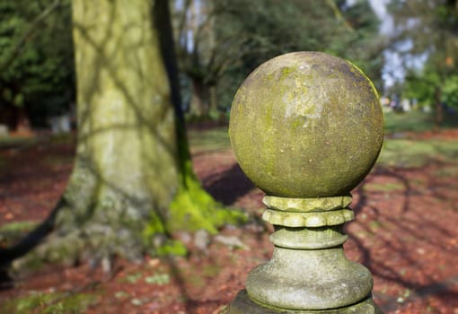 Mossy globe design statue with green trees and grass in background