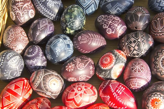 Easter eggs painted on table sold at market outdoor street fair illuminate sunlight.