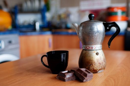 An image of coffee maker with cup and chokolate