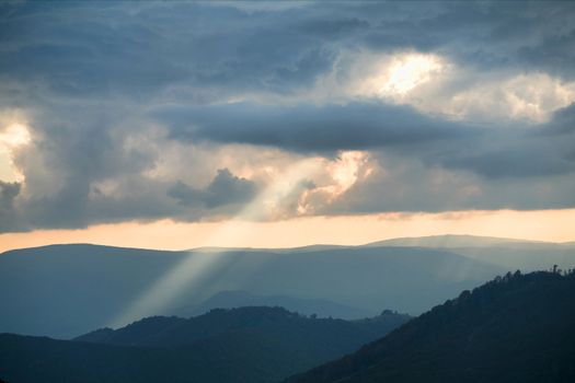 An image of sunrays going through grey clouds