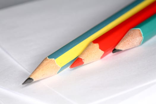 Closeup image of three pencils laying on white paper