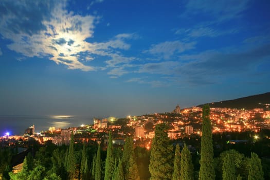 Night city. Houses with illuminated windows and moantains.