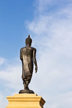 back of black buddha statue against blue sky in thai temple