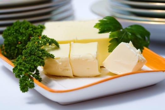 Stock photo: an image of blocks of fresh butter and parsley on a plate