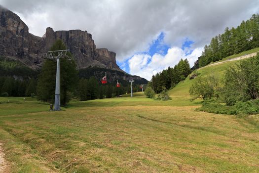 meadow and cableway beneath dolomites peak in Badia Valley, Italy
