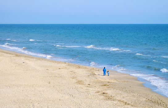 Mammy and daughter are walking along the shore