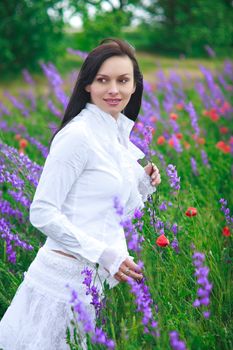 A beautiful young woman smiling, walking in a field of flowers