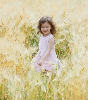 A little girl sing and dance in a field of rye