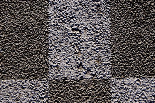 Background macro closeup of an asphalt road and markings on it. Pebble-based street.