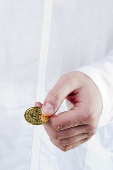 Close-up photograph of a golden coin in a man's hand.