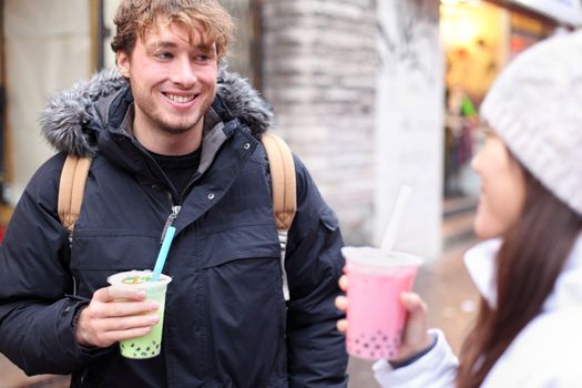 Friends in city drinking bubble tea / pearl milk tea smiling happy and talking in chinatown of Montreal, Quebec, Canada.