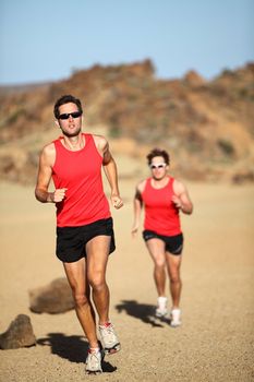 Runners running training for marathon competition in beautiful desert landscape. Two men sport fitness models during exercise run.