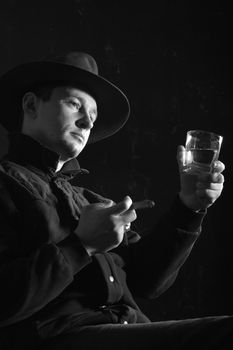 An monochrome image of a man with cigar and glass