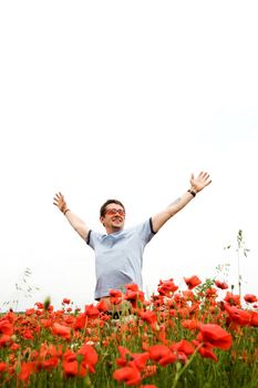 A man in the field with poppies with his hands spread