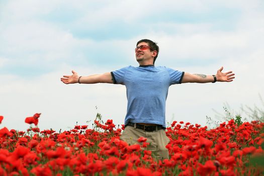 A man in the poppy-field with his hands spread