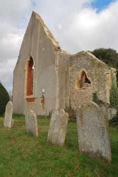 portrait view of ruined church with gravestones