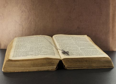 old bible book with brown background and silver cross
