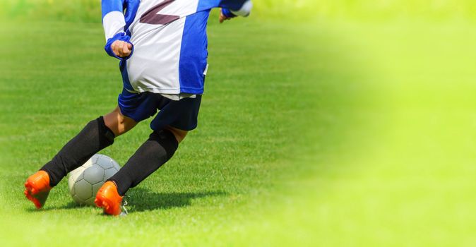 Young school child Soccer player legs dribbling in a match 