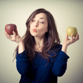 beautiful woman choosing red or yellow apples on gray background