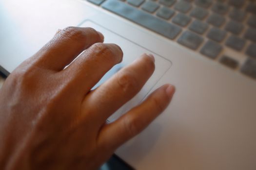 Right hand on pad of silver laptop on table