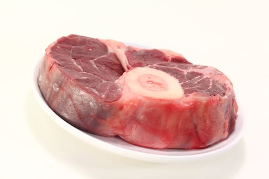 raw leg slice on a plate before light background