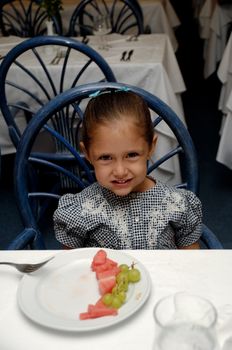 A sweet child sitting at table in a restaurant smiling