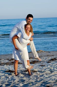 A happy young woman and man having fun on beach. 