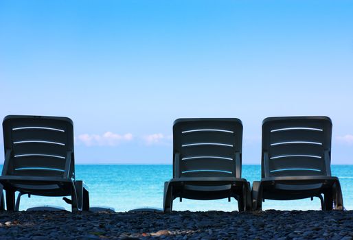 Three chairs on a seashore in a tropic location