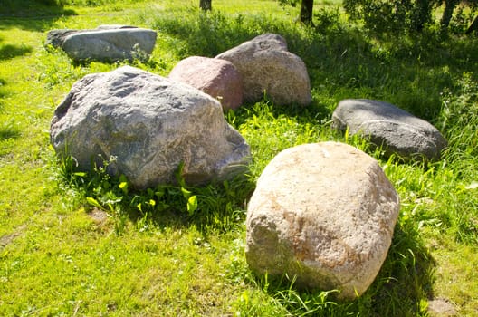 Large stones in garden on verdant meadow. Rural farm scenery.
