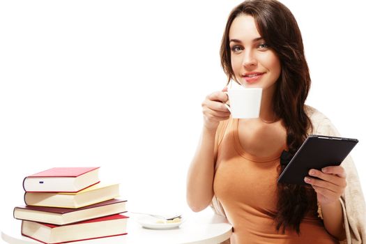 smiling woman with ebook reader, coffee at a table with books on white background