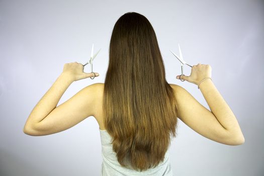 Girl with 2 pairs of scissors ready to cut her long hair