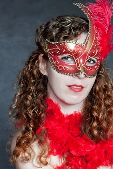 Beautiful young lady in a red mysterious venetian mask