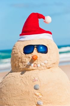 Snowman made from Sand at the beach, smiling in Camera